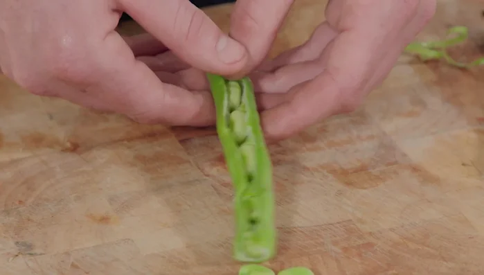 Préparer les fèves et les petits pois. Les ajouter aux artichauts dans la poêle et faire sauter.