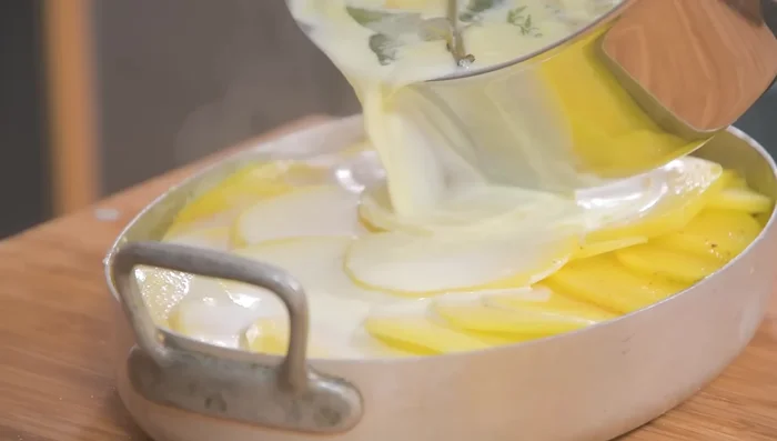 Verser le lait infusé sur les pommes de terre jusqu'à ce qu'elles soient recouvertes. (254.43)