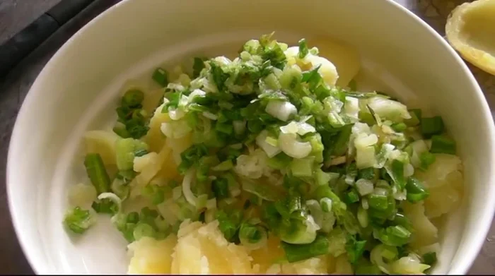 Dans les pommes de terre évidées, ajouter les oignons, le sel, l'ail, la ciboulette, la crème fraîche et le fromage. Bien mélanger pour obtenir une pâte homogène.