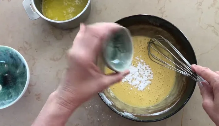 Préparer la pâte à clafoutis (quantités non précisées dans la transcription, ajuster selon une recette classique). Incorporer 6g de levure chimique (pas un sachet entier). Ajouter 4 cuillères à soupe d'eau pour fluidifier la pâte.