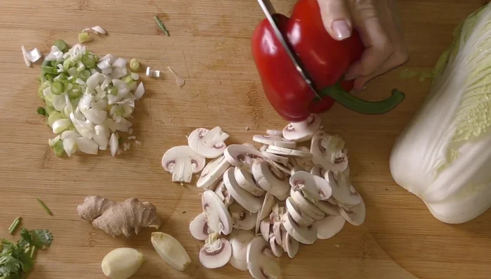 Préparer les autres légumes : couper les champignons en lamelles (95.04), le poivron en lamelles (103.079), la carotte en lamelles (136.02) et émincer finement le chou chinois (122.34).