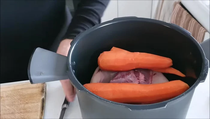 Dans la cocotte, placer la langue de bœuf, les carottes, les oignons et le fond de veau.