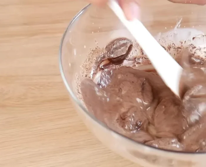 Verser le mélange chaud sur le chocolat noir en trois fois, en remuant vivement entre chaque ajout pour faire fondre le chocolat et émulsionner.