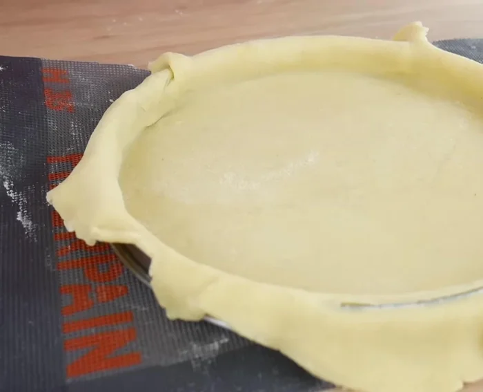 Retirer l'excédent de pâte, égaliser les bords et piquer le fond de tarte.