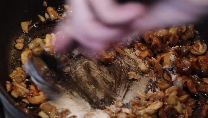 Ajouter de la farine aux oignons et champignons, puis incorporer l'ail, le lait pour faire une sauce.