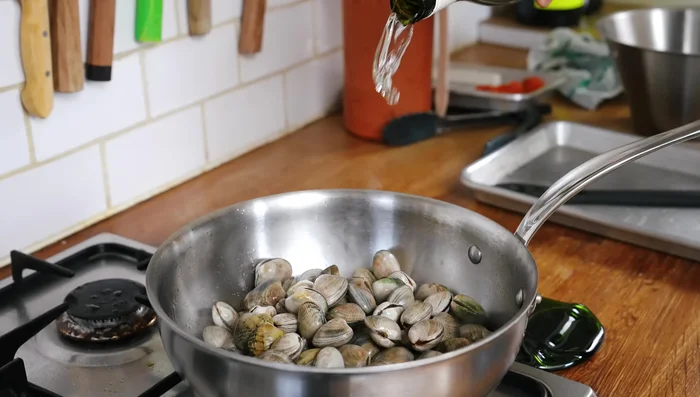Ajouter les palourdes, le vin blanc, couvrir et cuire 2-3 minutes jusqu'à ouverture complète.