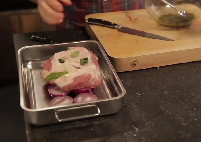 Déposer le gigot sur les oignons dans le plat. Étaler la marinade sur le gigot.