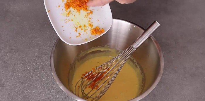 Ajouter la moitié des zestes aux jaunes d'œufs sucrés et mélanger.