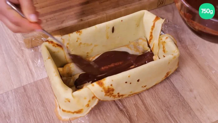 Répéter l’opération pour former 3-4 étages de rouleaux de crêpes, en intercalant des couches de ganache entre chaque étage. Recouvrir le haut avec des bords de crêpes.