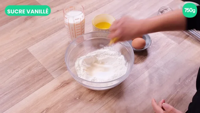 Préparation de la pâte à crêpes : Mélanger la farine, le sucre et le sucre vanillé dans un grand saladier. Faire un trou au centre et y déposer les œufs. Mélanger au fouet. Ajouter petit à petit le beurre fondu et fouetter. Ajouter le lait petit à petit en fouettant pour éviter les grumeaux.