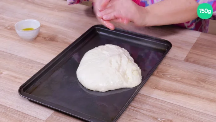 Étaler la pâte sur la plaque à pizza avec les mains, du centre vers les bords.
