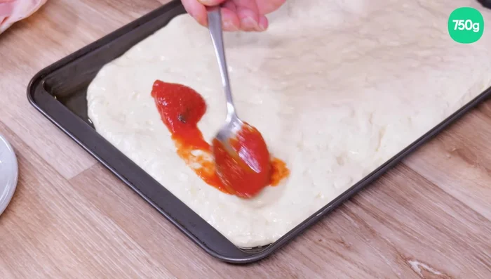 Étaler la sauce tomate sur la pâte, en laissant 2 cm de bord libre.