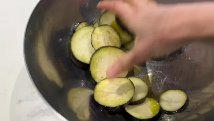 Préparation de la salade d'aubergines: Couper l'aubergine en rondelles, saler, ajouter de l'huile d'olive et griller à la poêle ou à l'appareil à gaufres. Mélanger avec de l'oignon vert, du fromage turc, du sel, du poivre et de l'huile d'argan. Réfrigérer.