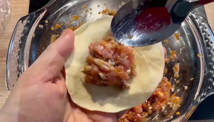 Mettez un peu de farce et une crevette au centre de chaque galette de pâte.