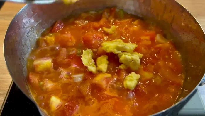Une fois les tomates fondantes, ajouter les omelettes. Laisser cuire à feu doux pendant 5 minutes pour que les omelettes absorbent le jus de tomate.