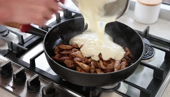 Verser la béchamel sur le mélange poulet-champignons-oignons. Mélanger et ajouter de la crème fraîche pour détendre la sauce.