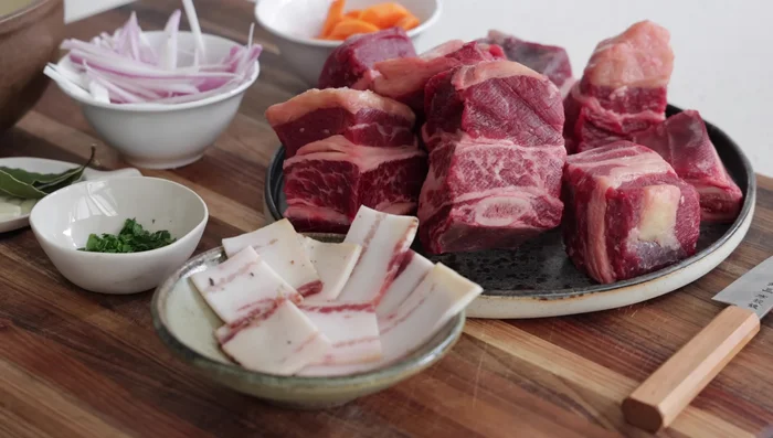 Préparer la marinade : dans un grand plat, mélanger les carottes, oignons/échalotes, ail, feuille de laurier, thym, et le vin de Madère.
