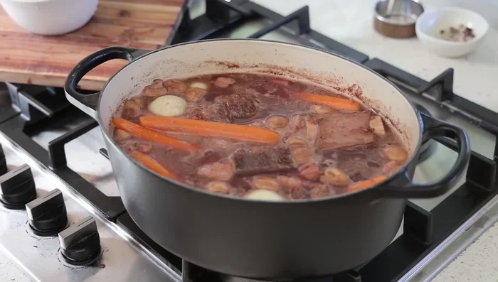 Transférer la cocotte au four préchauffé à 160°C et cuire pendant 2h30 à 3h, jusqu'à ce que la viande soit tendre.