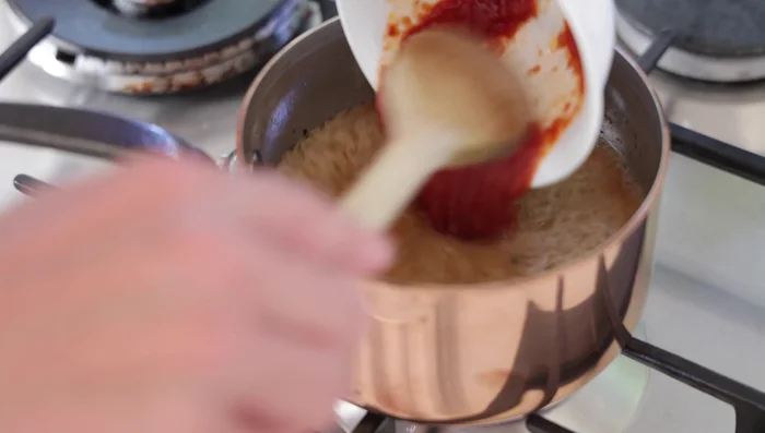Ajouter le bouillon brun réduit et la tomate. Mélanger. Porter à ébullition à feu moyen et réduire pendant 5-6 minutes, jusqu'à obtenir la consistance souhaitée. Écumer les impuretés et la graisse en surface si nécessaire.
