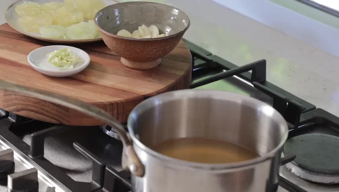 Faire bouillir le bouillon : porter le bouillon de poulet à ébullition pour le réduire et concentrer la saveur. Ajouter les gousses d'ail.