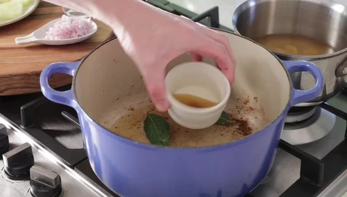 Déglacer la cocotte : ajouter les feuilles de laurier et faire caraméliser les morceaux bruns au fond de la cocotte.