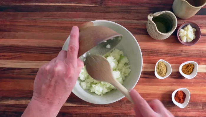 Dans un bol, mélanger les oignons hachés, l'ail écrasé, le paprika, le cumin, les épices marocaines, le sel, le poivre, l'huile d'olive et l'eau.