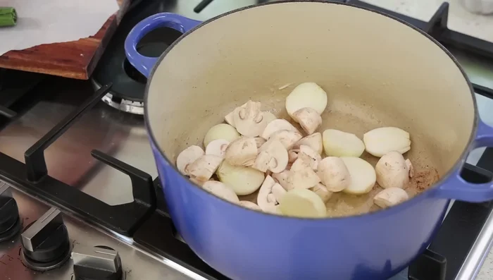 Ajouter les oignons et les champignons. Faire suer à feu doux sans coloration. (294.3)