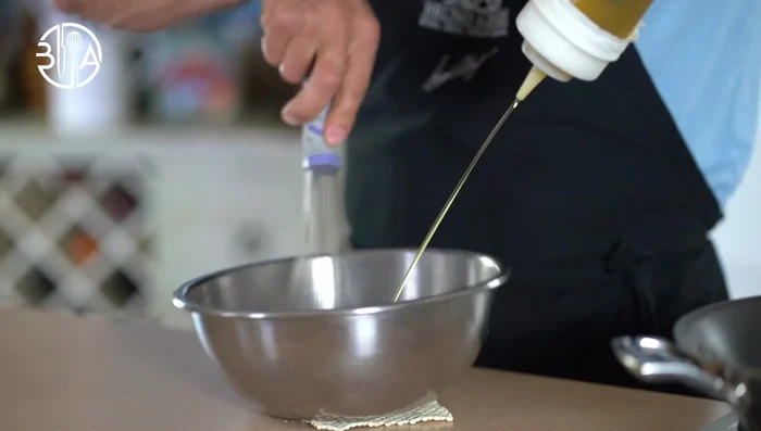 Préparation de la vinaigrette : Fouetter le vinaigre de mangue avec de l'huile d'olive, du suprème de citron haché, du jus de citron, du sel et du poivre.