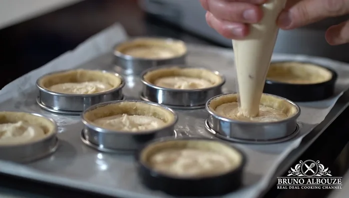 Cuire les tartelettes à blanc, les remplir de crème d'amandes et cuire au four pendant 30 minutes.