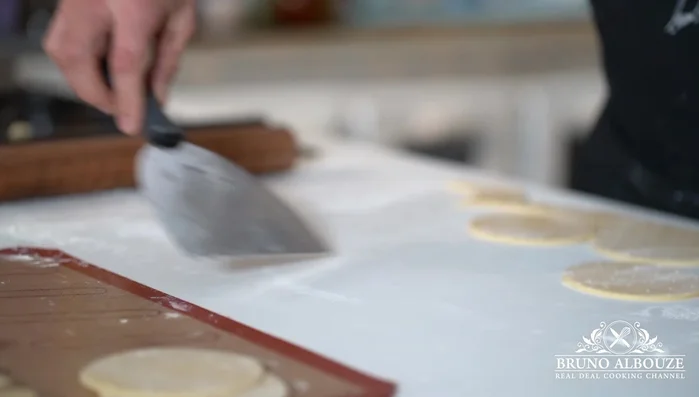 Préparer la pâte sablée : Étaler la pâte sur une feuille de papier sulfurisé, la diviser en disques légèrement plus grands que les anneaux à pâtisserie. Réfrigérer pendant 30 minutes, puis ajuster l'épaisseur des disques, les façonner en fines rondelles et les placer au congélateur.