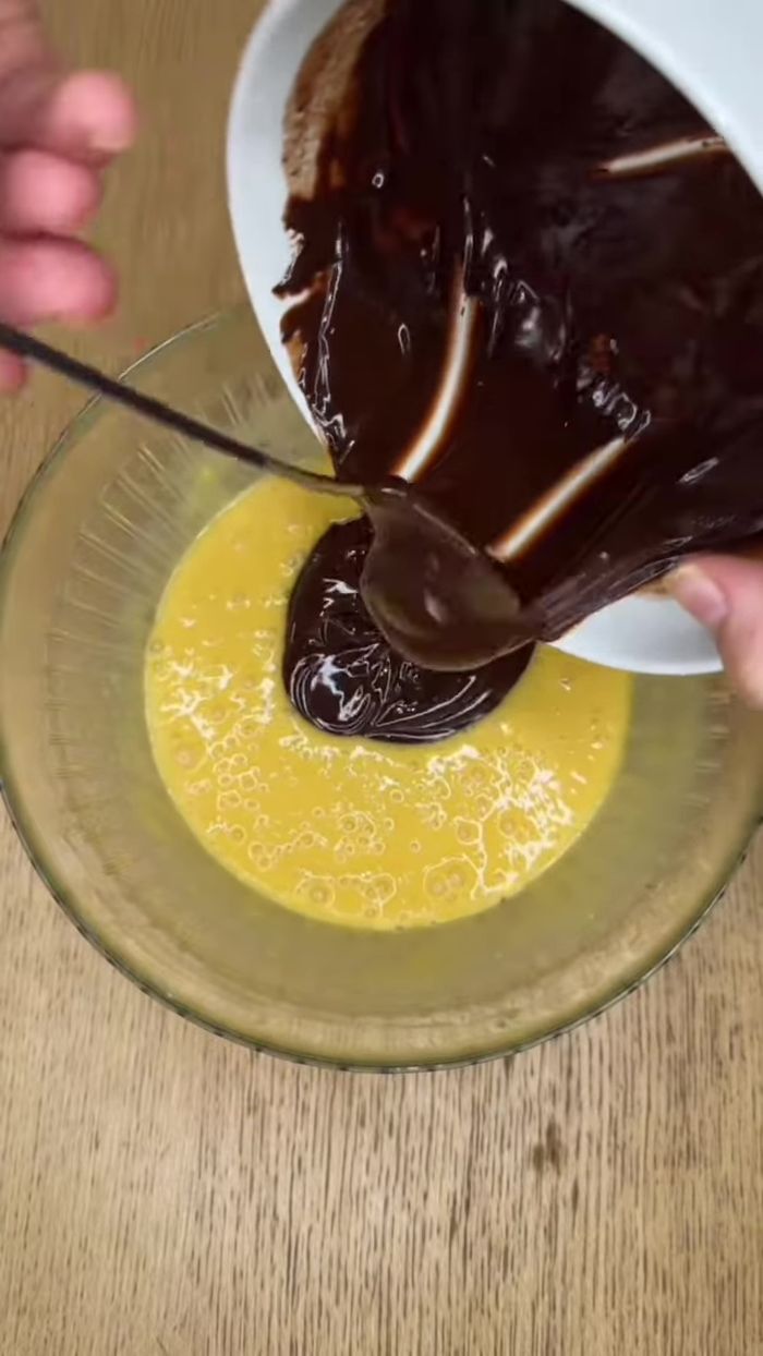 Verser le chocolat fondu dans la pâte à fondant. Fouetter jusqu'à obtenir un résultat brillant et homogène.