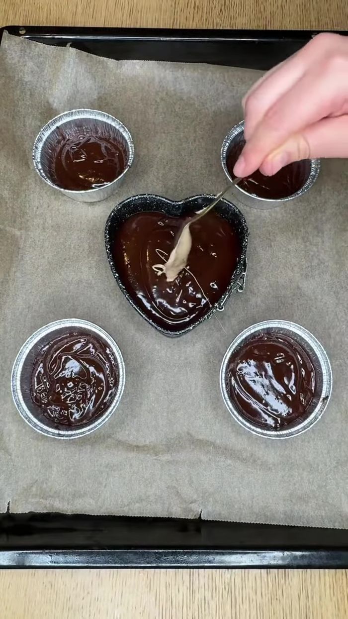 Ajouter une portion de pâte à tartiner Kinder Bueno au centre de chaque moule.