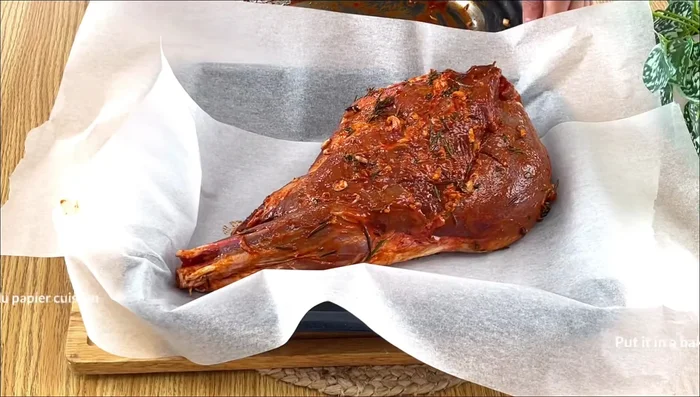 Placer le gigot dans un plat à four, le couvrir de papier cuisson, puis l'envelopper de papier aluminium.