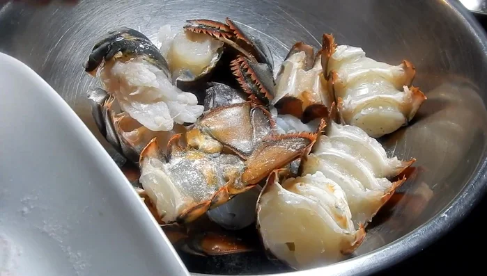 Assaisonner les morceaux de homard avec du sel, du poivre citronné et l'assaisonnement vert. Ajouter la tomate hachée et bien mélanger. Laisser mariner au réfrigérateur pendant au moins quelques heures, idéalement toute la nuit.