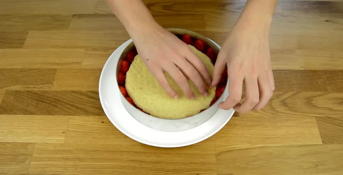 Montage du fraisier : Déposer un disque de génoise imbibé de sirop dans le cercle à pâtisserie. Disposer les fraises de décoration tout autour sur le rhodoïd. Ajouter une couche de crème diplomate entre les fraises, puis une couche plus importante au centre. Ajouter des cubes de fraises au milieu. Déposer le second disque de génoise.