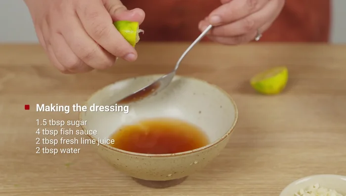 Préparez la vinaigrette : mélanger 1.5 cuillère à soupe de sucre, 4 cuillères à soupe de sauce de poisson, 2 cuillères à soupe de jus de citron vert, 2 cuillères à soupe d’eau, 1 cuillère à soupe d’ail émincé et du piment haché (319.6).