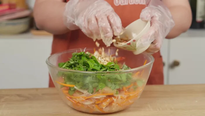 Incorporez les herbes fraîches et la plupart des arachides. Ajoutez le reste de la vinaigrette. Mélangez (416.319).