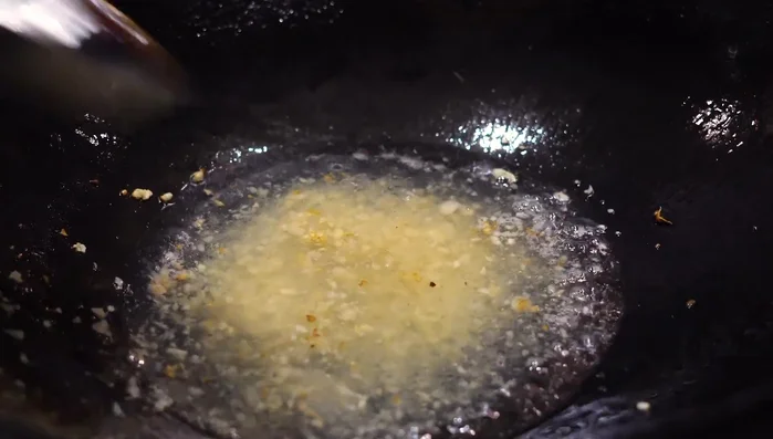Ajoutez un peu de vin de cuisine, du sel, du sucre et de la sauce soja noir. Mélangez le tout à l'ail.