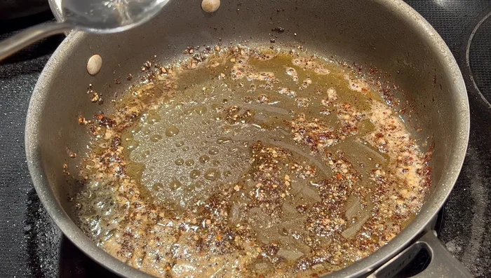Déglacer la poêle avec 3 cuillères à soupe de vinaigre blanc, en grattant bien le fond pour récupérer les sucs de cuisson.