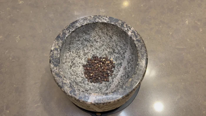 Concasser les grains de poivre au mortier pour en extraire la saveur tout en gardant des morceaux croquants.