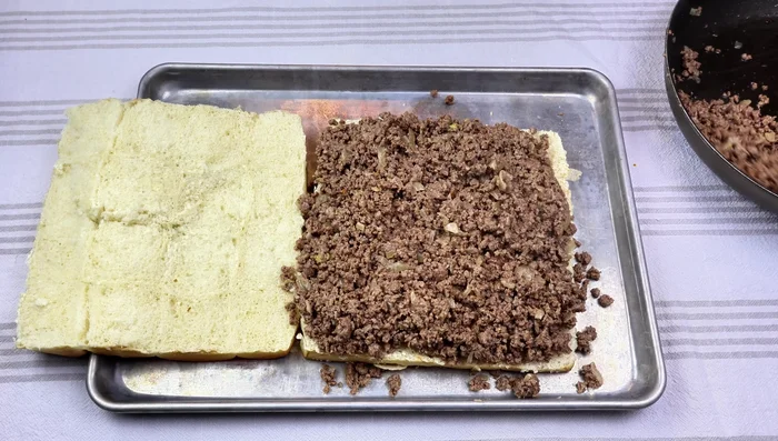 Assemblage des hamburgers: Étaler la sauce sur les rouleaux, ajouter le bœuf haché, le fromage cheddar, et le dessus des rouleaux. Badigeonner de beurre et parsemer de graines de sésame.