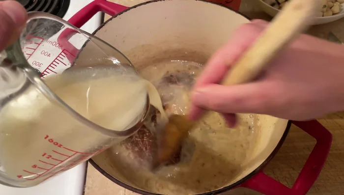 Incorporer le liquide de cuisson des pétoncles (vin blanc réduit et eau) au roux, en mélangeant jusqu'à obtenir une sauce lisse.