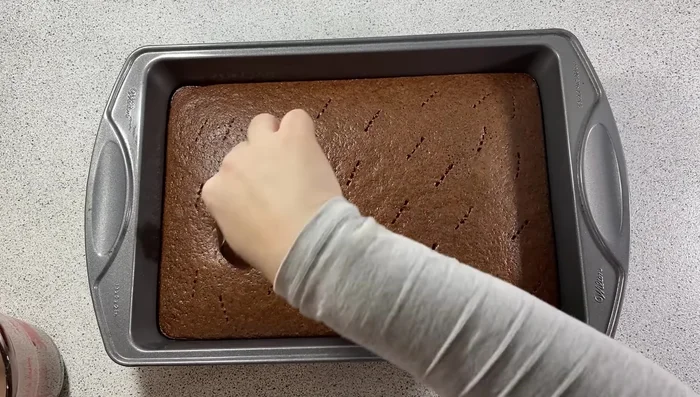 Sortir le gâteau du four, le piquer et imbiber avec le mélange au chocolat chaud.