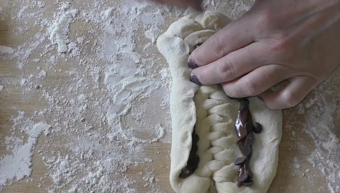 Rabattre les bords vers le centre, en pinçant la base et les extrémités pour fermer la brioche.