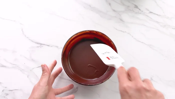 Réfrigérer le cheesecake pendant au moins 6 heures ou toute la nuit. Avant de servir, fouetter la ganache restante pour créer une mousse. Décorer le cheesecake avec la mousse de ganache et les petits chocolats noisette.