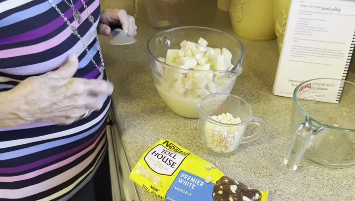 Incorporez les cubes de pain imbibés de beurre et les pépites de chocolat blanc au mélange.