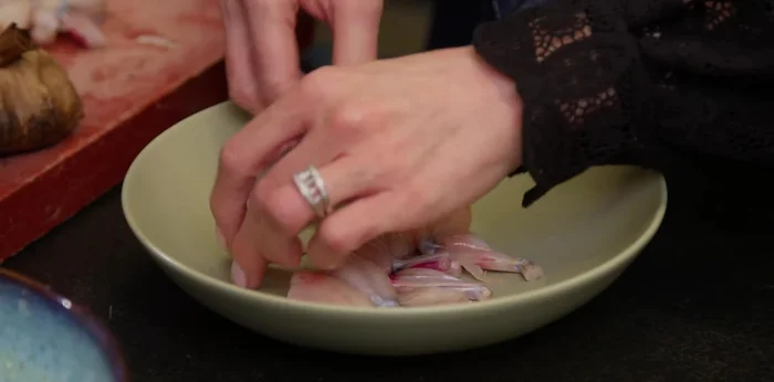 Assaisonner les cuisses de grenouilles avec du sel et du poivre. (134.08)