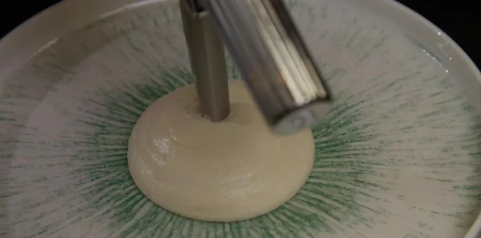 Dresser : commencer par la purée de persil au siphon, ajouter les cuisses de grenouilles, l’écume d’ail noir, un peu d’huile de persil, du poivre et du Kumbuawa pour relever le goût. (396.039)