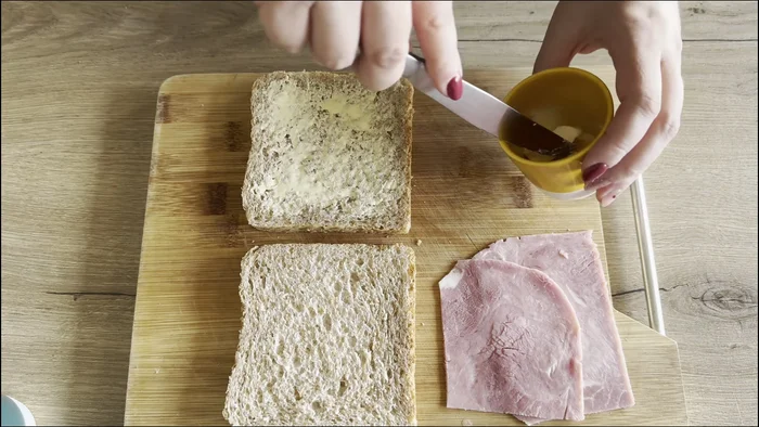 Badigeonner légèrement les deux tranches de pain de beurre.