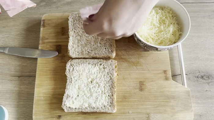 Sur une tranche de pain, ajouter le jambon et une poignée de gruyère.